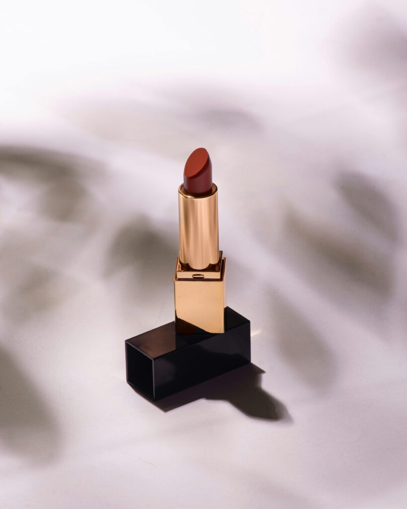 A luxurious red lipstick with gold casing on a white background with shadow effects.